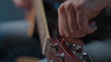 Hairy mans hand tuning a guitar adjusting its peg in slow motion - Close up shot