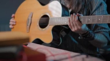Long-haired guitarist teaching online how to hold a guitar to his audience - Close up shot