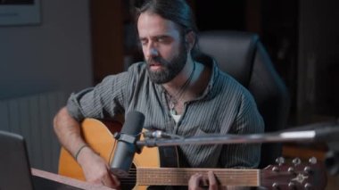 Young attractive guitarist playing an online concert because of the pandemic - Middle shot