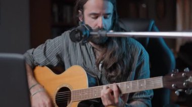 Caucasian musician playing a guitar song online in his YouTube studio - Close up shot