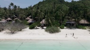 An aerial view of a romantic couple walking on beautiful tropical beach. An amazing view of nature - 4K Horizontal video