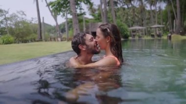 Havuzda sevişen bir çiftin tutkulu bir öpücüğünü yakından çek. Çift birlikte romantik vakit geçiriyor - 4K Yatay Video