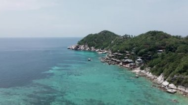 Kumsalın kıyısındaki bir İHA 'nın hava görüntüsü. Mavi su ve yeşil dağ da görüldü - 4K Yatay video