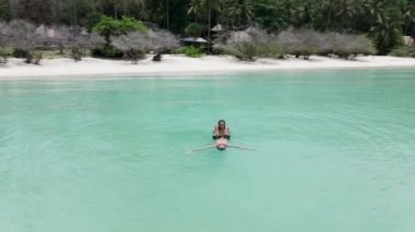 Yaz tatilinde turkuaz bir suda yüzen rahat bir çiftin İHA çekimi - 4K Yatay video