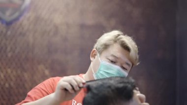 A commercial video of a barber is totally engrossed in setting clients hair with comb 4K Horizontal video