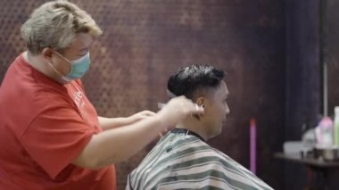 4K Horizontal Video Dükkanı 'nda erkek berberin orta kesiminin saçını keserken yan görüntüsü