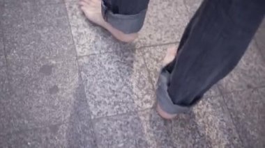 Close-up shot of man tiptoeing around the city barefoot - Horizonal video