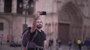 Male backpacker sends a selfie to his friends group chat in front of Valencias cathedral - Horizonal video
