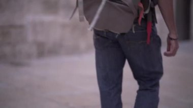 Follow shot of backpackers dirty feet walking around with people in the back of the scene. - Horizonal video