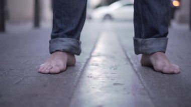 Close up of barefoot feet reveals a young mans face and walking in the street - Horizonal video