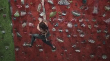 Wide shot of a professional climber training in artificial rock wall - Horizontal video