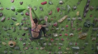 Strong athletic woman lets herself fall in front of rock wall in slow motion - Horizontal video