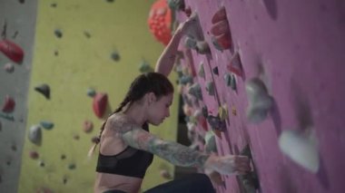 Low angle of young athlete climbing up rock wall - Horizontal video