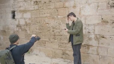 Professional film analog photographer and moody male model on outdoor photoshoot for fashion magazine or commercial advertising. - 4K Horizontal video