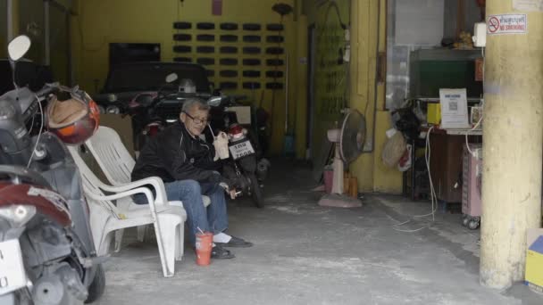 Old Male Rider Sitting Garage Drinking Cold Beverage Cigarette Hand — Vídeos de Stock