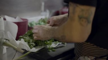 Male chef hands sort parsley branches on kitchen counter, close view - 4K Horizontal video
