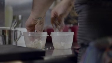 Close view of male chef fingers crumbling cheese into container - 4K Horizontal video
