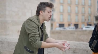 Close up shot of a male street magician showing magic tricks with stack of cards to locals pedestrians on a summer morning. - 4K Horizontal video