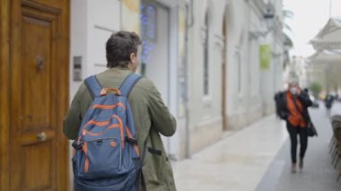 Back view of magician walking on the street for showing tricks to the people. - 4K Horizontal video