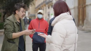 Close up view of a male Magician showing street magic trick with cards to the locals passing by on a bright sunny day. - 4K Horizontal video