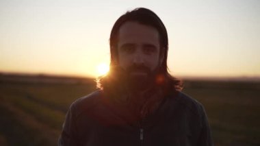 Close up of masculine caucasian man looking at the camera with sun rays from behind - Horizontal video