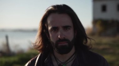 Close up of young caucasian looking at the camera in front of abandoned house in slow motion - Horizontal video