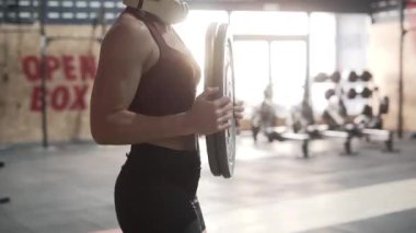 Unrecognizable fitness woman carrying dumbbells around the gym in sportswear - Horizontal video