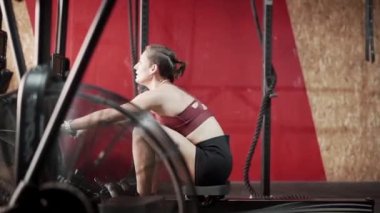 Bodybuilder exercising at the rowing machine on training session - Horizontal video