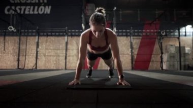 Caucasian woman doing push ups on a mat in big fitness room - Horizontal video