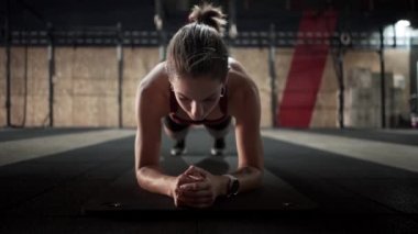 Athlete in plank position looks at the camera and then gets up - Horizontal video