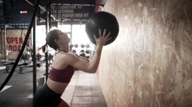 Spanish woman working out at the gym throwing and taking exercise ball - Horizontal video