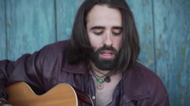 Male artist practicing his singing and guitar playing outdoors. Close up. - Horizontal video