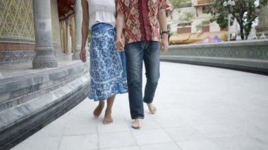 Japanese guy and transgender Thai couple in masks visiting and praying at Wat Ratchabophit Sathitmahasimaram Buddhist Ratchaworawihan temple, walking together hand in hand - gimbal following shot - 4K