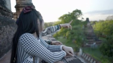 Two Happy Thai girls talking on a high-ground terrace of a Wat Yai Chai Mongkhon temple in Ayutthaya, Thailand - bust shot - 4K Horizontal