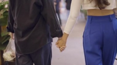A young couple in love walking on the street holding hands and enjoying each others company - 4K Horizontal video