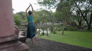 Back View Of A Happy Woman Tourist Wearing Halter Top And Flared Skirt, Doing A Ballet Dance Outside The Old Temple In Ancient City Muang Boran, Thailand. - Rack Focus - 4K Horizontal video