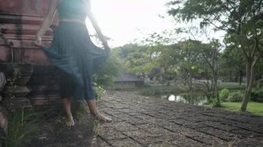 A Woman In Blue Clothing Gracefully Twirling In The Cobblestone Pathway Within The Ancient Siam Museum, Thai Ban Mai, Thailand. Slow-motion - 4K Horizontal video