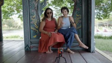 Women Vloggers Recording Video For Travel Channel In Ancient City Museum Park, Thai Ban Mai, Thailand - wide shot - 4K Horizontal video