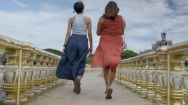 Back View Of Two Women Walking On The Bridge Of Ancient City Museum Park During Daytime Near Bangkok, Thailand. Low Angle - 4K Horizontal video
