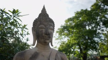 Close-up of concrete Buddha statue head against sun on sunset in Wat Yai Chai Mongkhon temple - 4K Horizontal