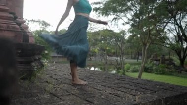 Female With Long Skirt Spinning And Enjoying Nature Scenery At Ancient City Museum Park In Thailand - medium shot - 4K Horizontal video