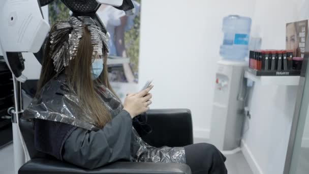 Young Female Using Her Phone While Getting Hair Treatment Salon — Stock videók