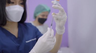 Thai doctor using syringe to extract solution from vial in beauty care procedure - 4K Horizontal video