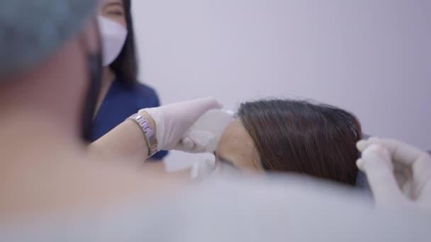 Doctor Assistant Holds Ice Pack Patients Forehead Preparing Botox Injections — Vídeo de stock