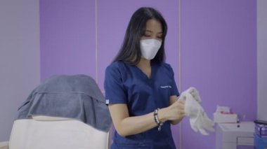 Aesthetic doctor puts on white gloves and picks up needle at her beauty salon in Bangkok - 4K Horizontal video