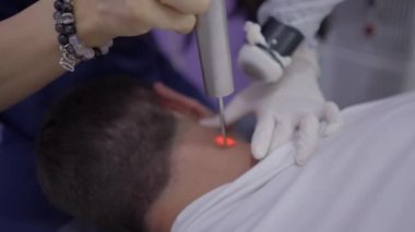 Faceless beautician uses laser device in anti aging therapy on patients neck - extreme close up shot - 4K Horizontal video