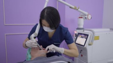 Asian doctor performs aesthetic treatment on patient with laser device - 4K Horizontal video