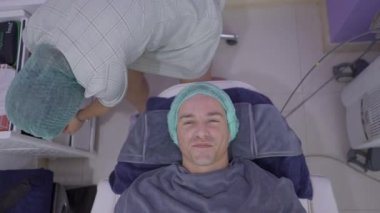 Happy man smiles while getting face prepared for cosmetic procedure in beauty salon in Bangkok - 4K Horizontal video