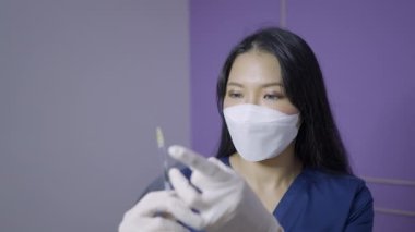 Asian doctor holds needle for aesthetic procedure and looks at the camera - 4K Horizontal video