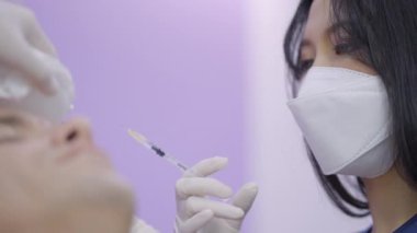 Asian doctor working at plastic surgery clinic performing botox treatment on patient - 4K Horizontal video